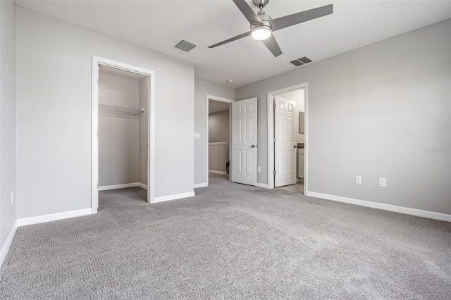 unfurnished bedroom featuring a spacious closet, light colored carpet, ceiling fan, ensuite bath, and a closet