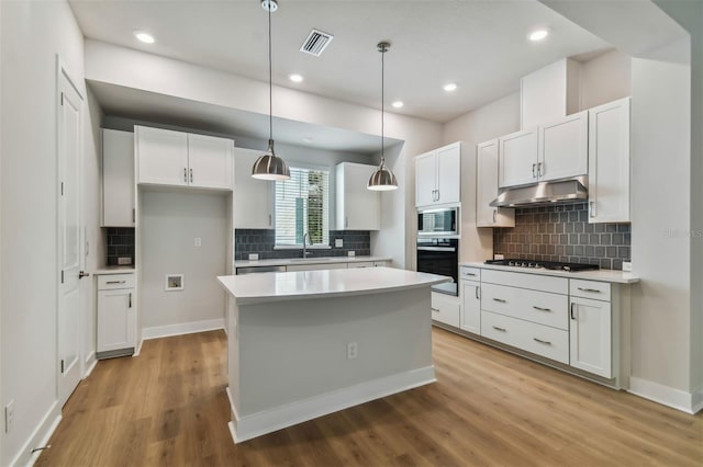 kitchen featuring light hardwood / wood-style flooring, white cabinets, pendant lighting, and appliances with stainless steel finishes