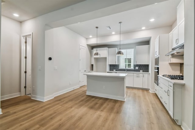 kitchen with a center island, stainless steel appliances, light hardwood / wood-style floors, decorative light fixtures, and white cabinets