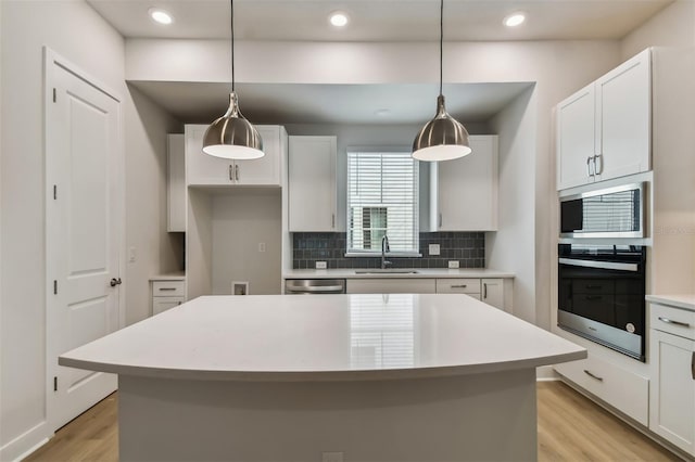 kitchen featuring appliances with stainless steel finishes, a center island, white cabinetry, and sink