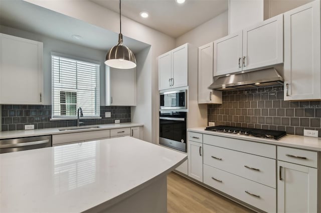 kitchen featuring sink, stainless steel appliances, pendant lighting, decorative backsplash, and white cabinets