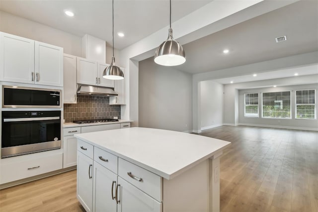 kitchen featuring stainless steel appliances, white cabinets, a center island, light hardwood / wood-style floors, and hanging light fixtures