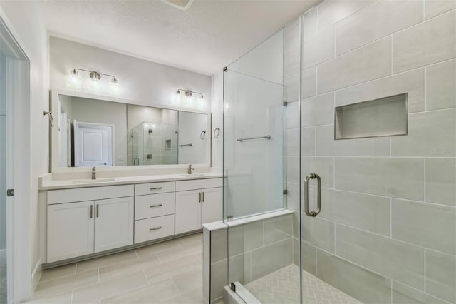 bathroom with a shower with door, vanity, and a textured ceiling