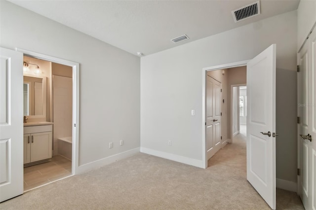 unfurnished bedroom with connected bathroom, light colored carpet, and sink