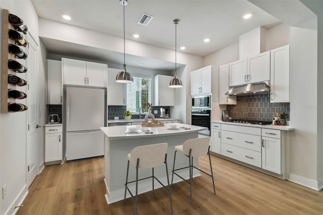 kitchen featuring black appliances, decorative light fixtures, white cabinetry, and light hardwood / wood-style flooring