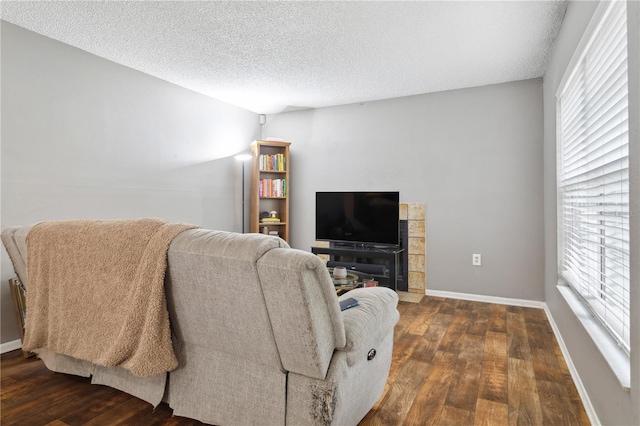 living room featuring a textured ceiling, dark hardwood / wood-style floors, and a healthy amount of sunlight