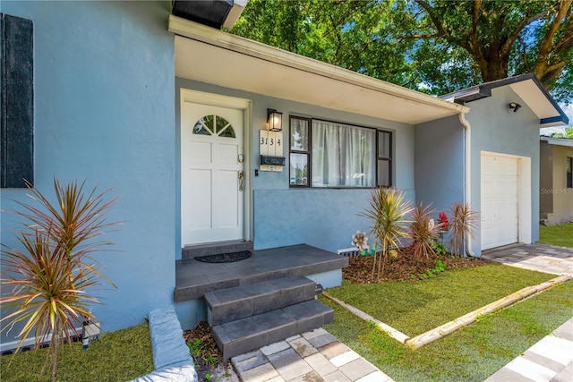 doorway to property featuring a garage and stucco siding