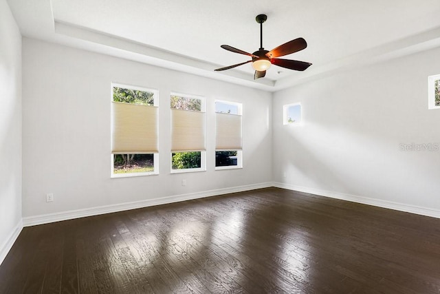 spare room featuring ceiling fan, dark wood-type flooring, and a raised ceiling