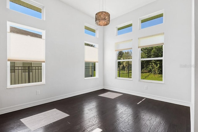 empty room with a high ceiling and dark hardwood / wood-style floors