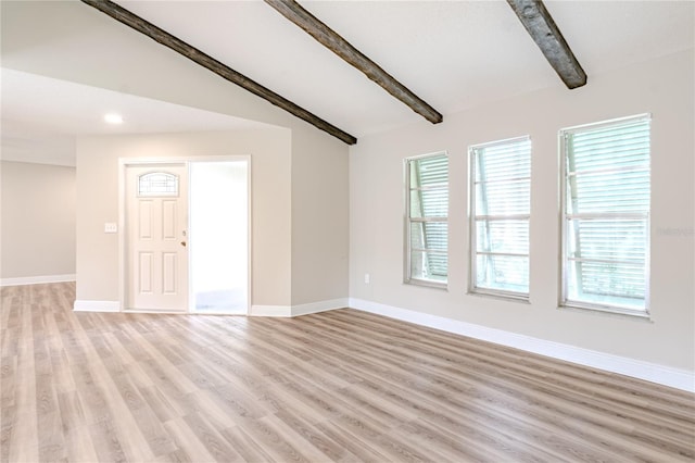 unfurnished living room featuring a healthy amount of sunlight, vaulted ceiling with beams, and light hardwood / wood-style floors