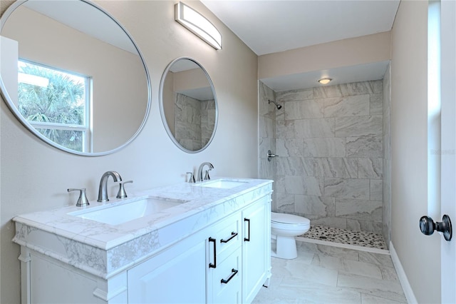 bathroom with vanity, toilet, and tiled shower