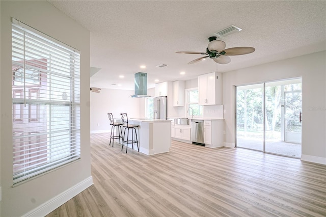 kitchen featuring white cabinetry, high end white refrigerator, a kitchen breakfast bar, stainless steel dishwasher, and island range hood