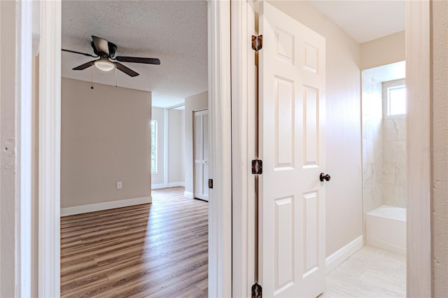 corridor featuring light hardwood / wood-style flooring and a textured ceiling