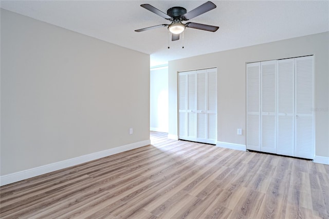 unfurnished bedroom featuring two closets, ceiling fan, and light hardwood / wood-style floors