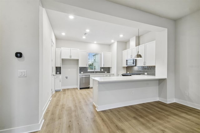 kitchen featuring kitchen peninsula, tasteful backsplash, stainless steel appliances, white cabinets, and light hardwood / wood-style floors