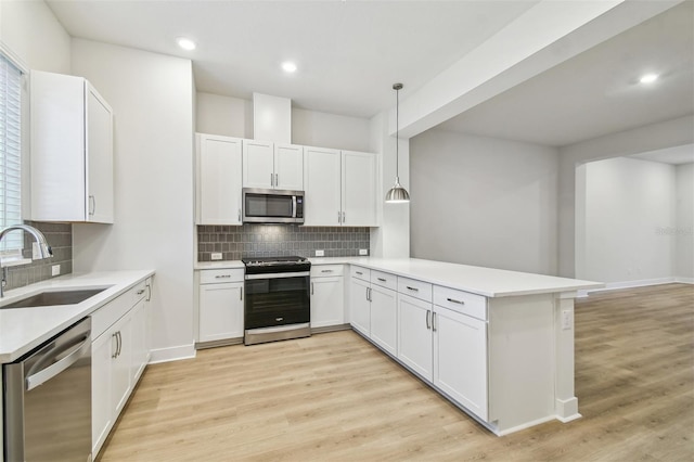 kitchen featuring sink, white cabinetry, stainless steel appliances, and hanging light fixtures