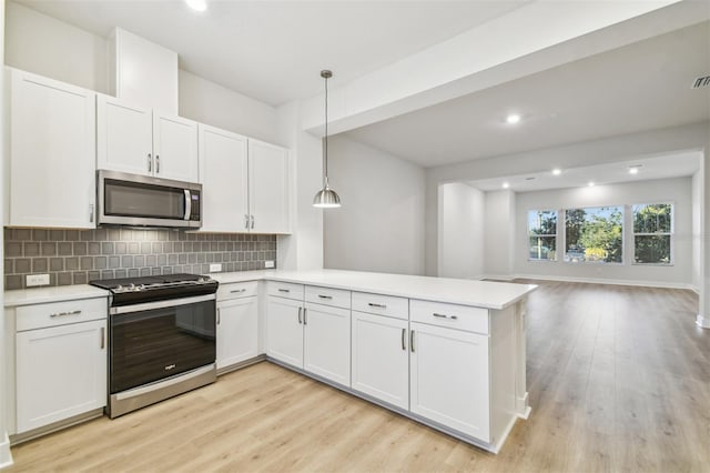 kitchen with white cabinets, hanging light fixtures, light wood-type flooring, appliances with stainless steel finishes, and kitchen peninsula