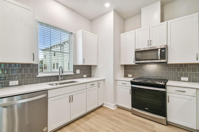 kitchen featuring white cabinets, decorative backsplash, stainless steel appliances, and light hardwood / wood-style flooring