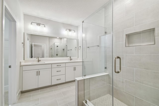 bathroom featuring vanity, an enclosed shower, and a textured ceiling