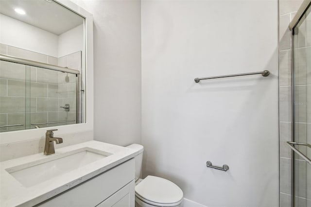 bathroom featuring vanity, toilet, and a shower with shower door