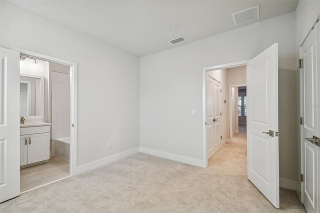 unfurnished bedroom featuring connected bathroom, light colored carpet, and sink