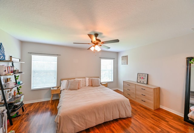 bedroom with dark hardwood / wood-style floors, ceiling fan, multiple windows, and a textured ceiling