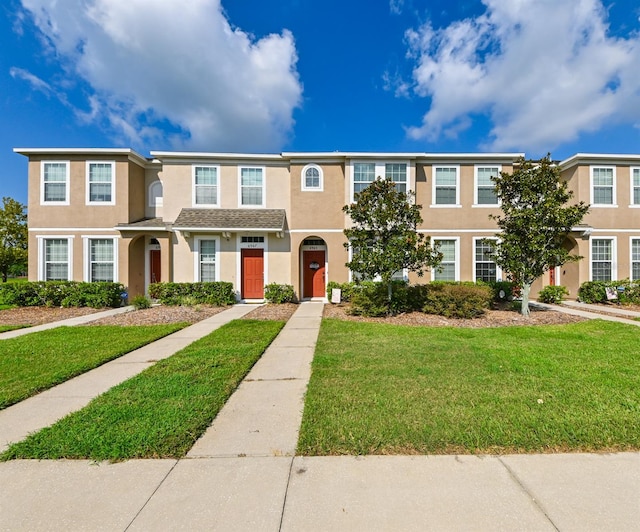 townhome / multi-family property featuring a front lawn