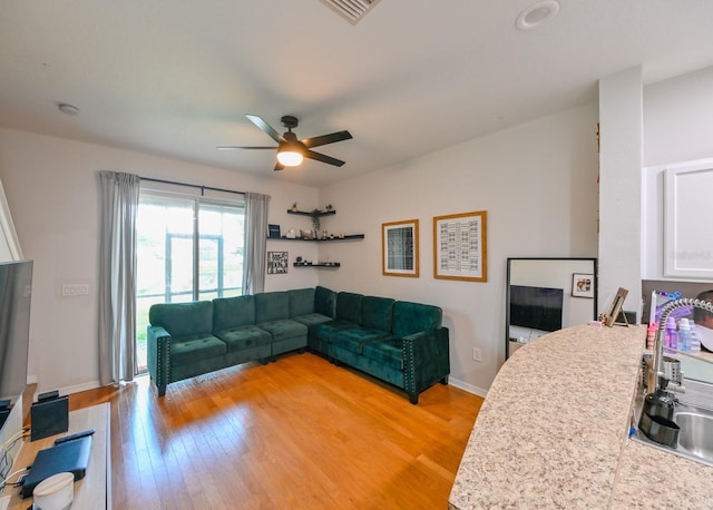 living room with light wood-type flooring, sink, and ceiling fan