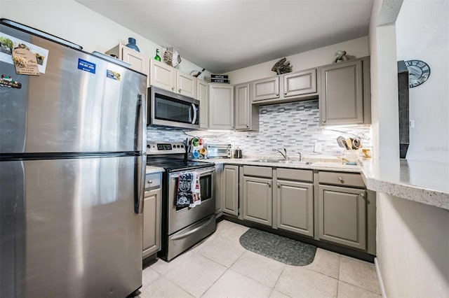 1611 Stevenson Dr, Clearwater, FL 33755 - kitchen with appliances with stainless steel finishes, gray cabinetry, a sink, and backsplash