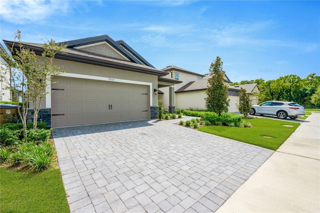 view of front of property featuring stone siding, decorative driveway, an attached garage, and stucco siding