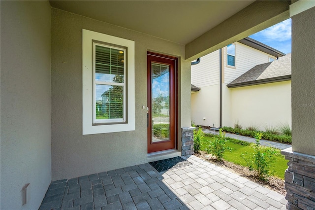 property entrance featuring a shingled roof and stucco siding