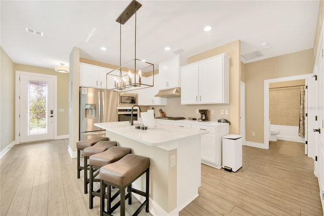 kitchen featuring white cabinets, appliances with stainless steel finishes, and an island with sink