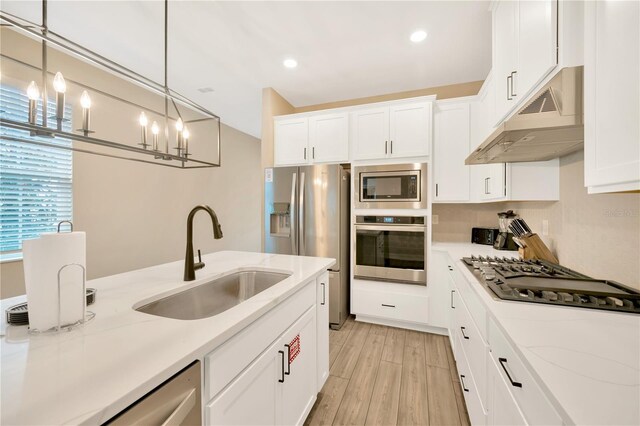 kitchen featuring sink, hanging light fixtures, light wood-type flooring, light stone countertops, and stainless steel appliances