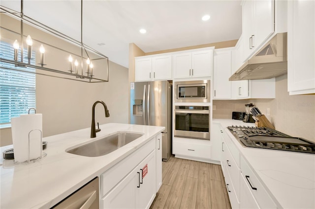 kitchen with stainless steel appliances, a sink, white cabinets, and under cabinet range hood