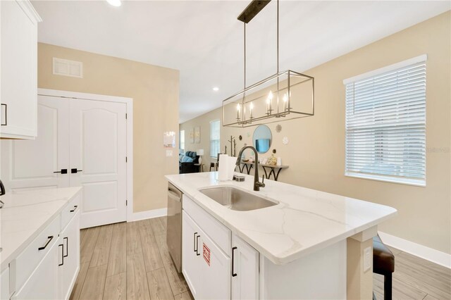 kitchen with sink, light wood-type flooring, an island with sink, white cabinetry, and pendant lighting