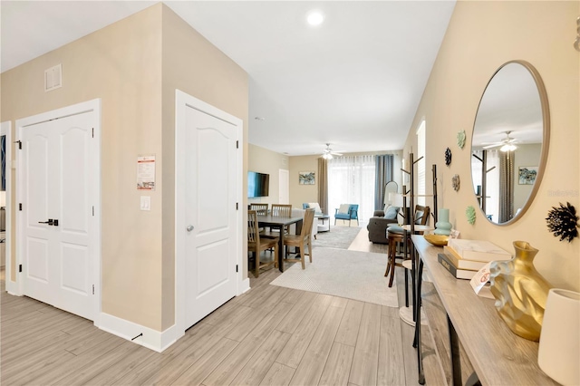 corridor featuring light wood finished floors, visible vents, and baseboards