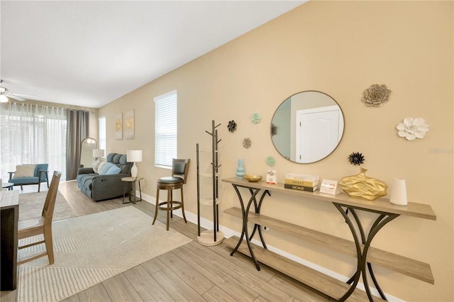 interior space featuring ceiling fan, plenty of natural light, light wood-style flooring, and baseboards