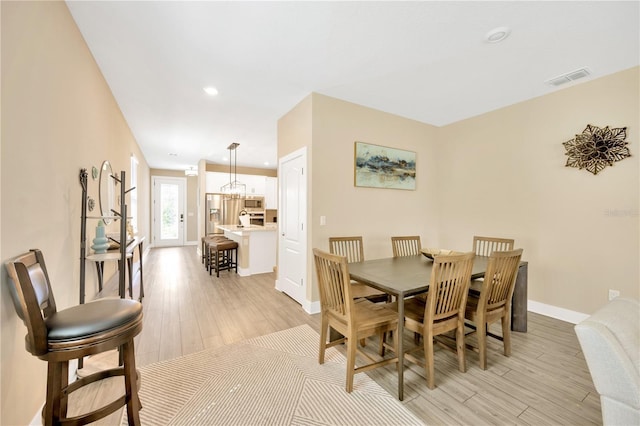 dining space featuring light wood finished floors, recessed lighting, visible vents, an inviting chandelier, and baseboards