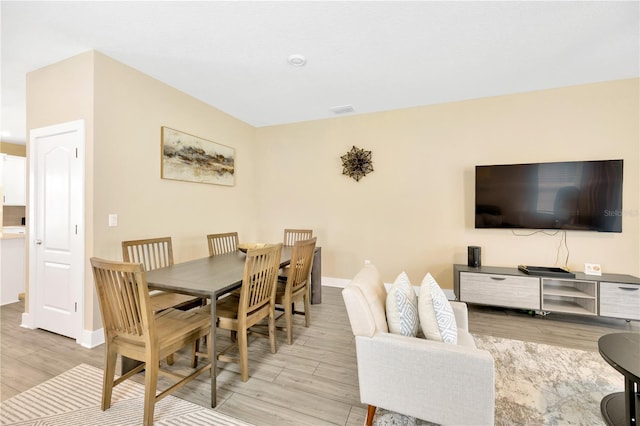 dining area featuring light wood finished floors, visible vents, and baseboards