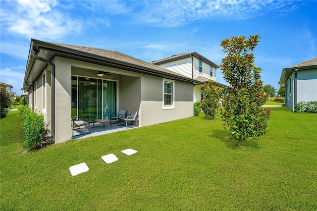 rear view of property with a lawn, a patio area, and stucco siding