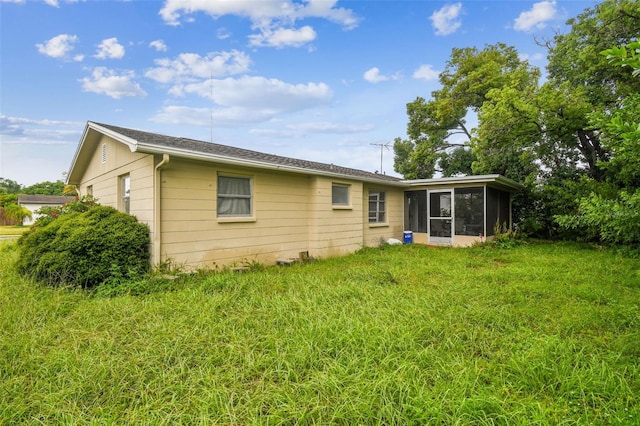 back of house with a sunroom and a lawn