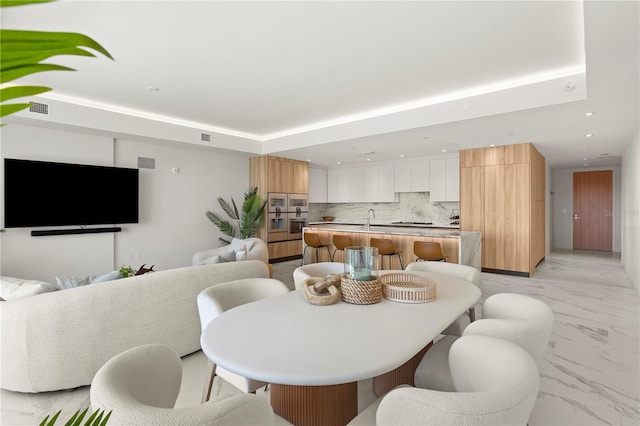 dining area with sink, a tray ceiling, and light tile patterned flooring