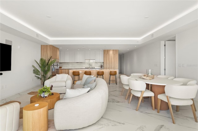 living room featuring a tray ceiling and light tile patterned floors