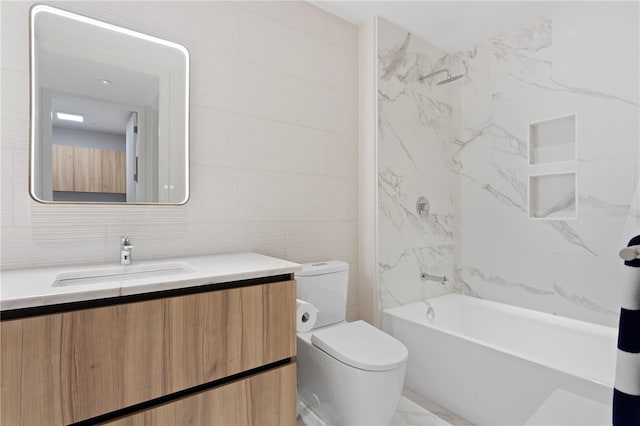 full bathroom with tiled shower / bath, toilet, vanity, and tile walls