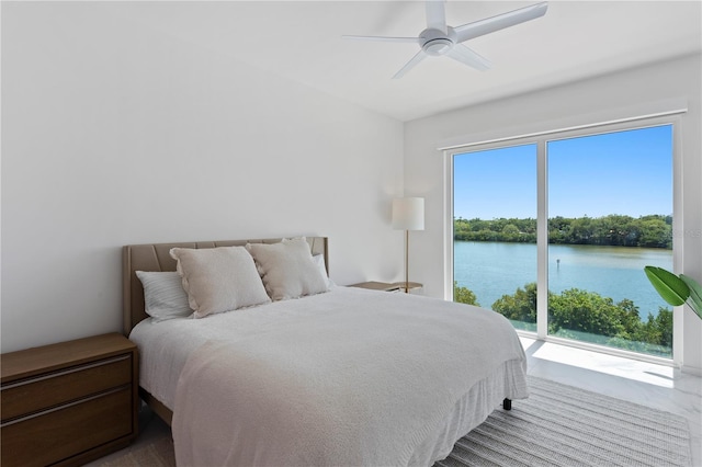 bedroom featuring ceiling fan and a water view