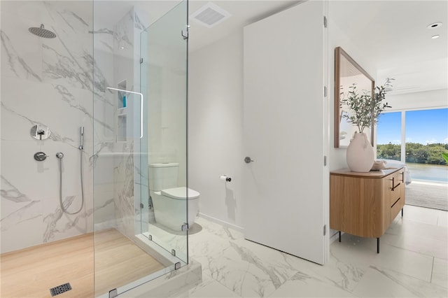 bathroom featuring toilet, tile patterned floors, and a shower with shower door