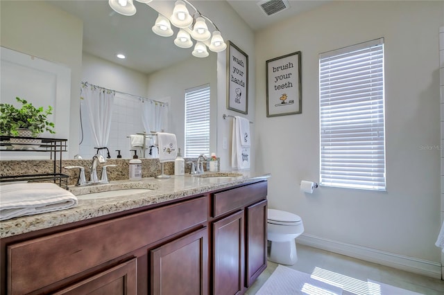 bathroom with dual vanity, toilet, and tile patterned flooring