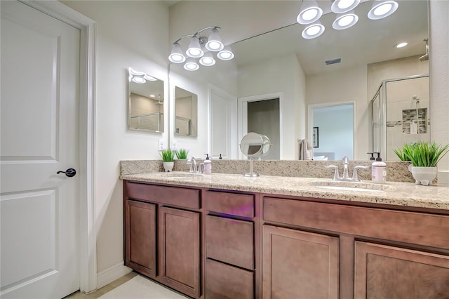 bathroom featuring an enclosed shower and dual vanity