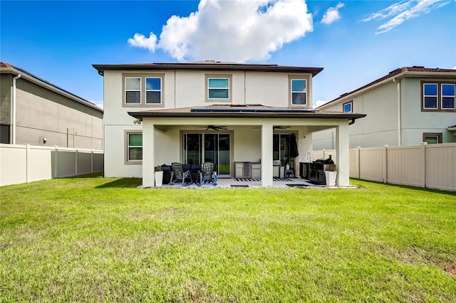 rear view of property featuring ceiling fan, a patio, and a yard