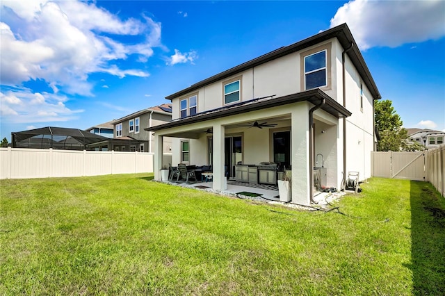 rear view of house featuring ceiling fan, a patio, and a lawn